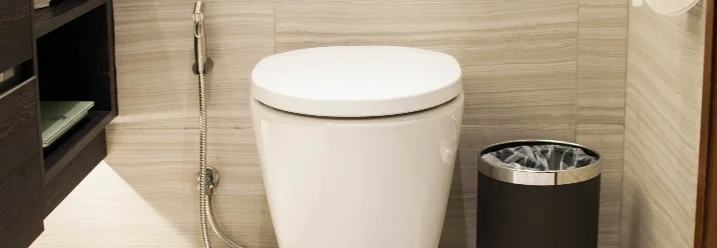 Moderne Toilette mit Duschfunktion neben Mülleimer